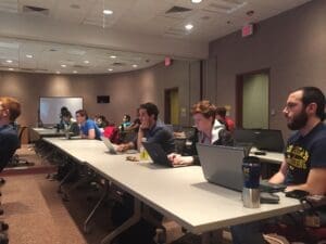 Graduate students at a table taking notes on computers