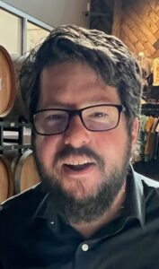 Man with beard and glasses wearing a black shirt.
