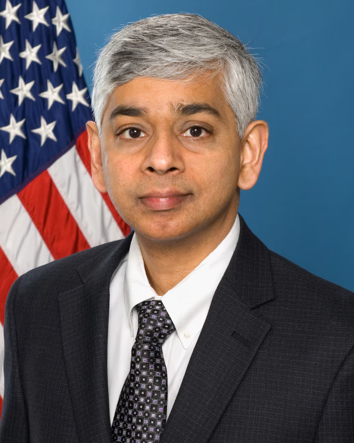 Man in a dark suite in front of the American flag