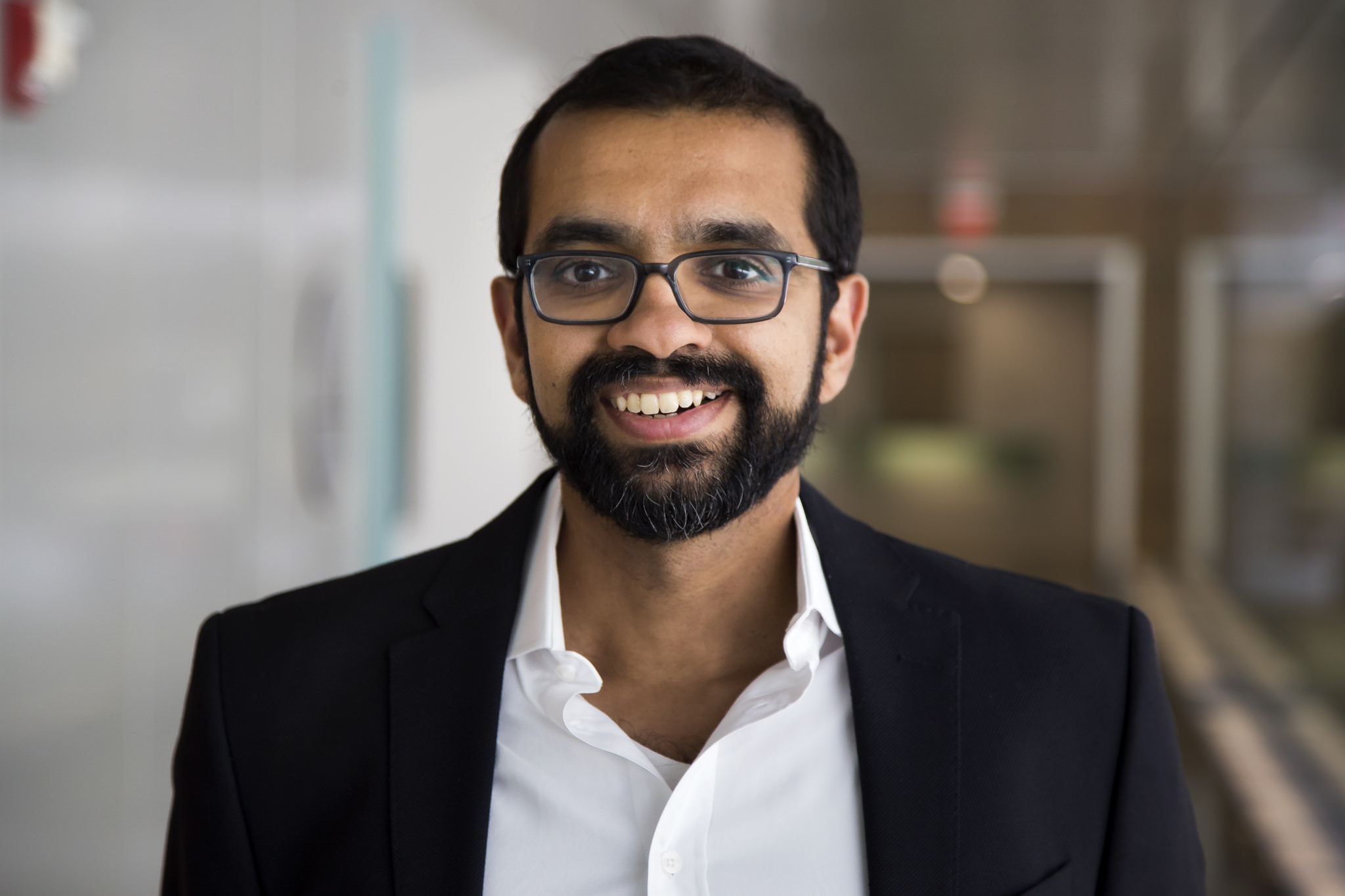 Headshot, wearing glasses, a collared shirt and sport jacket.