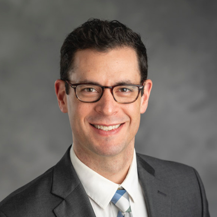 Headshot, wearing glasses, a collared shirt and sport jacket.