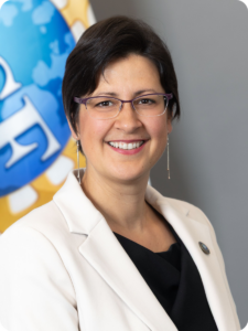Brown-haired woman wearing glasses and a white lab coat